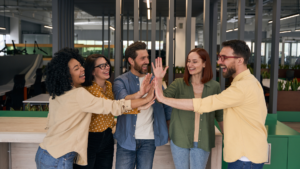 Team of co-workers high fiving one another to showcase corporate culture