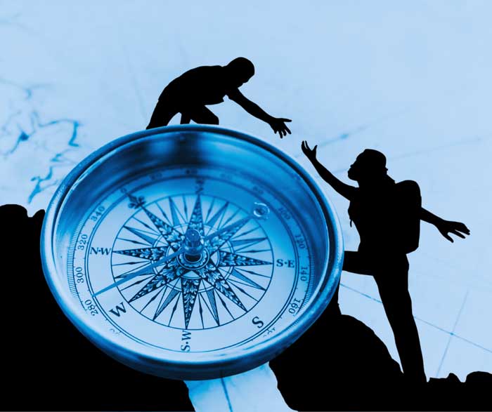 person at the top of a compass helping another person reach higher success