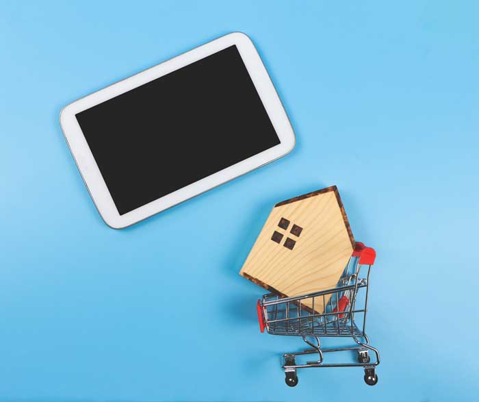 a tablet computer along with a shopping cart holding a house to represent online mystery shopping