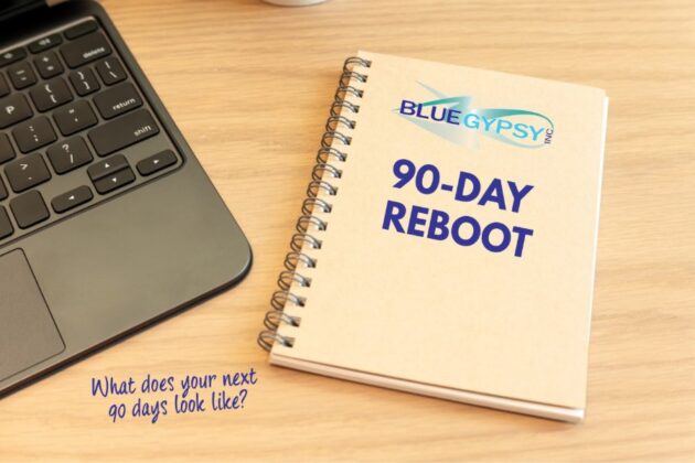 A spiral notebook labeled Blue Gypsy 90-Day Reboot sits on a wooden desk next to a laptop keyboard, with the handwritten question: What does your next 90 days look like?