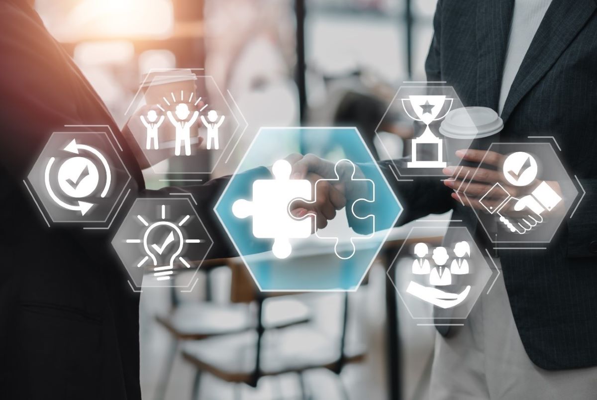 Two business professionals shaking hands with puzzle pieces and icons representing teamwork, leadership, and online sales success